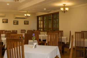 a dining room with white tables and wooden chairs at Sonikas Holiday Homes (Studio) in Candolim