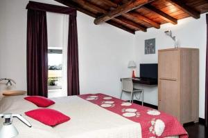 a bedroom with a bed with red pillows and a desk at Relais Villa D'Assio in Labro Rieti