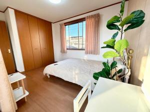 una camera da letto con un letto e una pianta in vaso di AiES新小岩 新小岩站走8分 繁华商店街旁 最大12人 直达机场秋叶原新宿 旅馆内带免费停车场庭院露台 邻公园 a Tokyo
