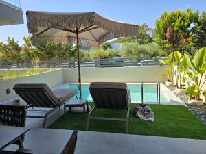 a patio with two chairs and an umbrella next to a pool at Adell Oasis in Iraklitsa