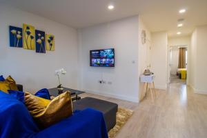 a living room with a blue couch and a white wall at Virexxa Bedford Centre - Alpha Suite - 2Bed Flat with Free Parking & Gym in Bedford +28 photos
