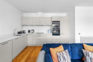 a living room with a blue couch and a kitchen at Panmure Apartment in Monifieth