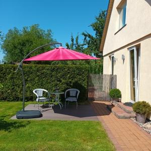 a patio with a table and chairs under a red umbrella at Baltā in Ventspils