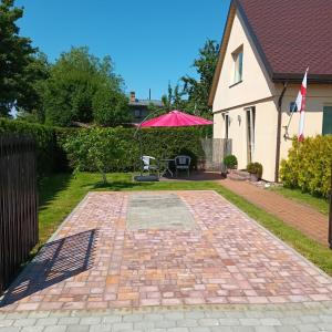 a brick patio with a pink umbrella in a yard at Baltā Studio with Patio & Free Parking in Ventspils +6 photos
