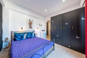 a bedroom with a purple bed and black cabinets at Relaxrooms in Lefkímmi
