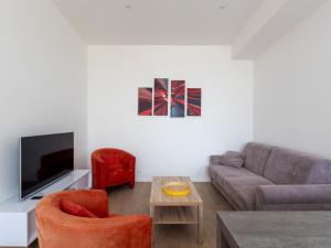 a living room with a couch and a tv at Ty Ker by Madame Est Servie in Pleumeur-Bodou