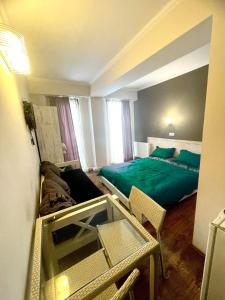 Schlafzimmer mit einem grünen Bett, einem Tisch und Stühlen in der Unterkunft Mgzavrebi Bakuriani in Bakuriani