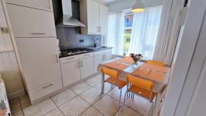 a kitchen with a table and chairs and a kitchen with white cabinets at Hello Zeeland - Vakantiewoning Schuurmanstraat 75b in Domburg