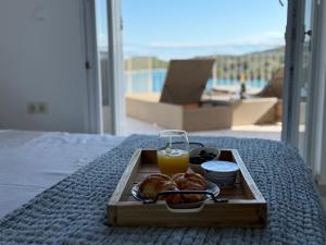 a tray of food and a glass of orange juice on a bed at SEASPRAY APARTMENTS TISNO in Tisno
