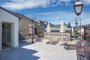 eine Terrasse mit Stühlen und Sonnenschirmen auf einem Gebäude in der Unterkunft Hotel De France in Mende