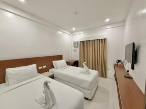 a hotel room with two beds and a flat screen tv at Cris Inn Samal in Samal