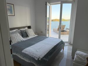 a bedroom with a bed with a view of a balcony at SEASPRAY APARTMENTS TISNO in Tisno +192 photos