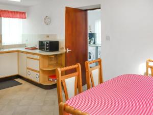 una cucina con tavolo e panna a scacchi rossa di Penlon Cottage a Gwydir