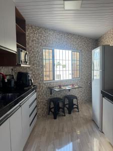Una cocina con una mesa y dos taburetes en ella. en Apartamento a beira do Rio Preguiça, en Barreirinhas