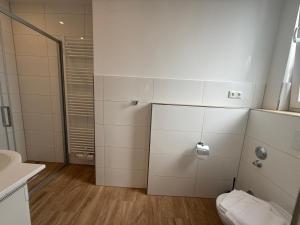 baño con paredes de azulejos blancos y aseo en Am Oland 11, hinten, en Büsum