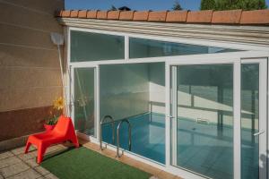 Un balcón con una silla roja y una piscina. en San Pelayo, en San Millán de Lara