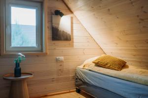 a bed in a wooden room with a window at Zakątek Wygonin Jacuzzi & Sauna w Lesie - KASZUBY in Wygonin