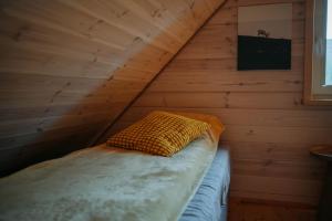a bed in a wooden room with a yellow pillow at Zakątek Wygonin Jacuzzi & Sauna w Lesie - KASZUBY in Wygonin