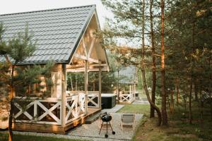 a house with a metal roof and a patio at Zakątek Wygonin Jacuzzi & Sauna w Lesie - KASZUBY in Wygonin