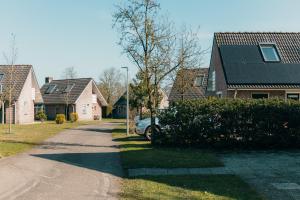 a house with a car parked on the side of a street at Vakantiepark Sallandshoeve in Nieuw-Heeten
