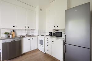 a kitchen with white cabinets and a refrigerator at Spacious 2BR Apartment in a Quiet Neighborhood & Free Parking in Turku