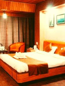 a hotel room with a large bed and a chair at Hotel Queen in Darjeeling