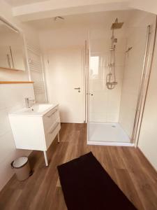 Un baño blanco con ducha y lavabo. en FeWo Leuchtturm, en Wilhelmshaven