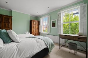 una camera da letto con pareti verdi, un letto e una scrivania di Spacious 3-Bedroom Family Home in Kingston with Garden, Smart TVs & Fast WiFi - Ideal for Longer Stays a Kingston upon Thames