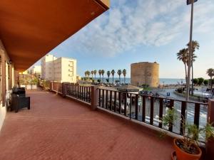 a balcony with a view of the ocean and palm trees at Casa del Sole Guest House in Alghero