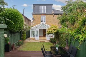 una casa con recinzione e tavolo e sedie di Spacious 3-Bedroom Family Home in Kingston with Garden, Smart TVs & Fast WiFi - Ideal for Longer Stays a Kingston upon Thames