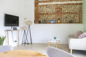 a living room with a couch and a brick wall at Le Cocon - Domaine du Colombier in Vaux-Marquenneville