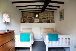 two twin beds in a bedroom with a brick wall at Cleave Cottage in Crackington Haven