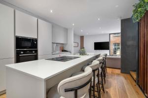 a kitchen with a white counter and a bar with stools at West Townhouse by CasaCity in Manchester