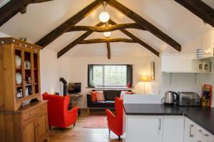 a kitchen with red chairs and a living room at Cleave Cottage in Crackington Haven
