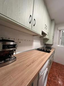 a kitchen with white cabinets and a wooden counter top at Apartamentos Ruidera in Ruidera +3 photos