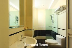 a bathroom with a sink and a toilet and a mirror at The V Hotel in Kuantan