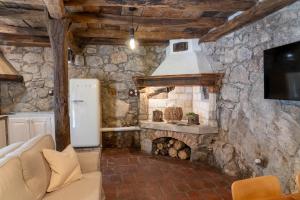 a stone kitchen with a refrigerator and a fireplace at Familija Lovrinovi Retreat - Relax&Reconnect in Zvoneće