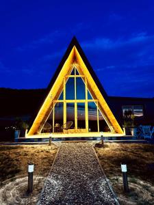 a pyramid shaped building with a lit up facade at night at Cozy Cabin House in Novi Pazar