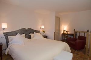 a bedroom with a large white bed and a chair at Hotel De France in Mende