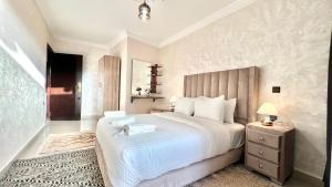 sypialnia z dużym białym łóżkiem i stolikiem nocnym w obiekcie sejour avec Jacuzzi et terrase au coeur du gueliz w Marakeszu