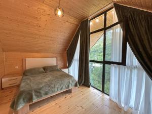 a bedroom with a bed and a large window at Iliaseuli's Cottage in K'vemo Jocho