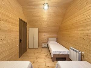a bedroom with two beds in a wooden room at Iliaseuli's Cottage in K'vemo Jocho