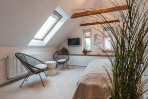 a attic bedroom with two chairs and a bed at Sedmé Nebe Apartmán in Děčín