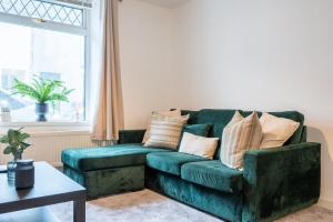 a green couch in a living room with a window at Silver Street by Tŷ SA in Troed-y-rhiw