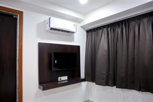 Una habitación con un televisor y una cortina negra. en Hotel Brook View, en Surat