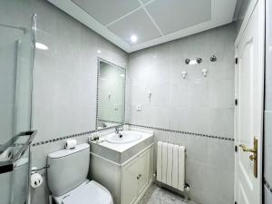 a white bathroom with a toilet and a sink at Luxury Suite La Tribuna del Paseo in Granada +17 photos