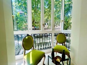 two green chairs sitting in front of a window at Luxury Suite La Tribuna del Paseo in Granada