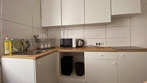 a kitchen with white cabinets and a sink and a microwave at Appartment Сoppenbrügge in Coppenbrügge