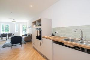 a kitchen with a sink and a living room at Birchgrove Christchurch Apartments Exclusively for 65s in Leatherhead +28 photos