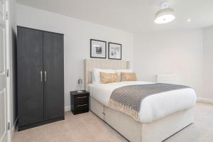 a bedroom with a large bed and a black cabinet at Birchgrove Christchurch Apartments Exclusively for 65s in Leatherhead
